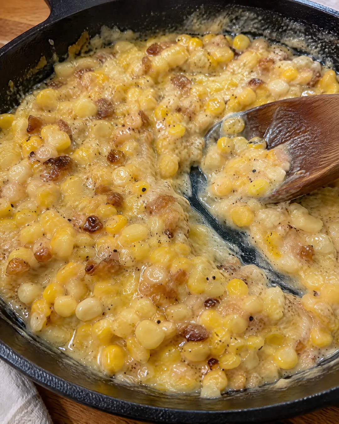 Thick creamy Southern fried corn in a cast iron skillet with golden browned bits scraped up from the bottom