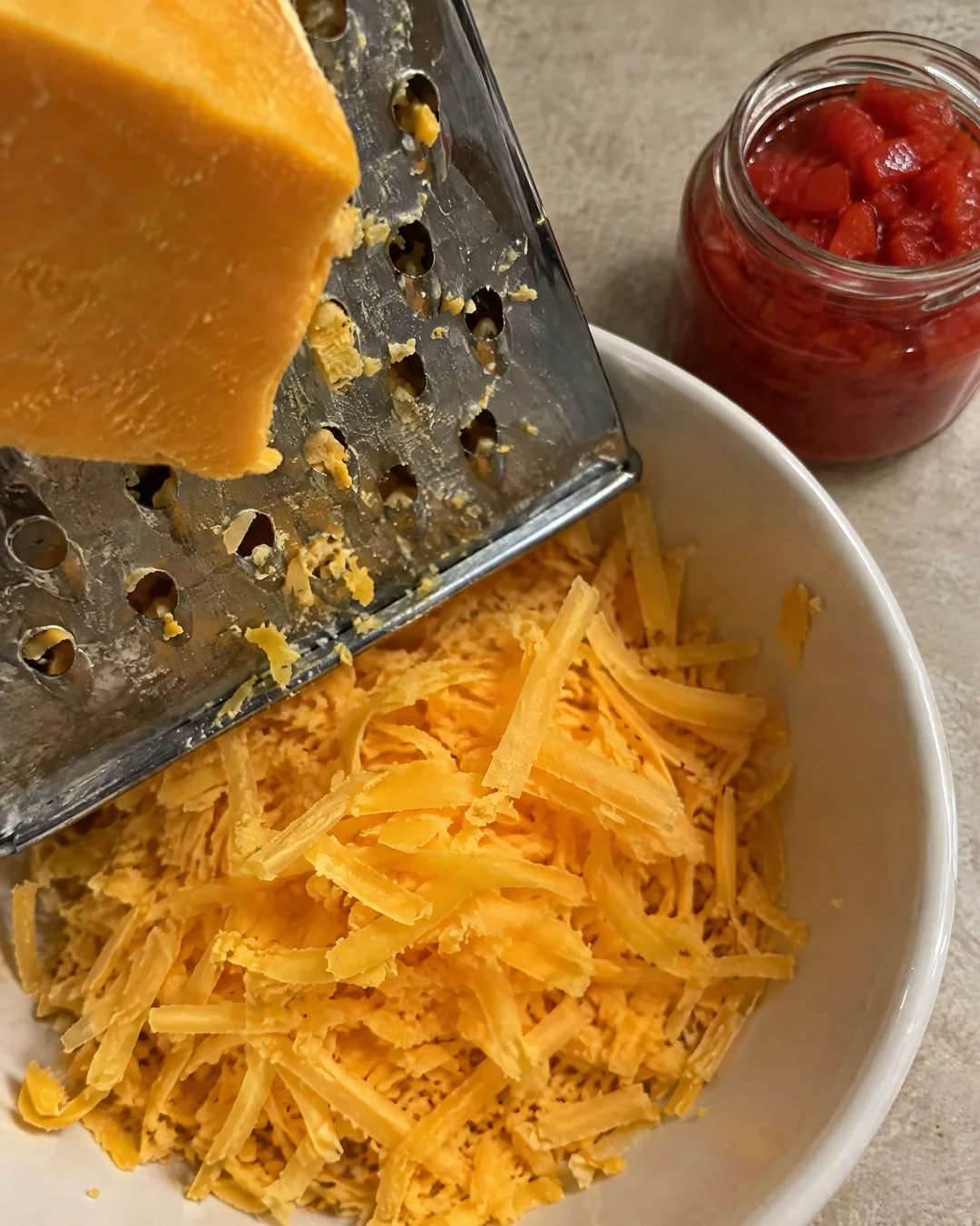 Grating a block of sharp cheddar by hand on a box grater