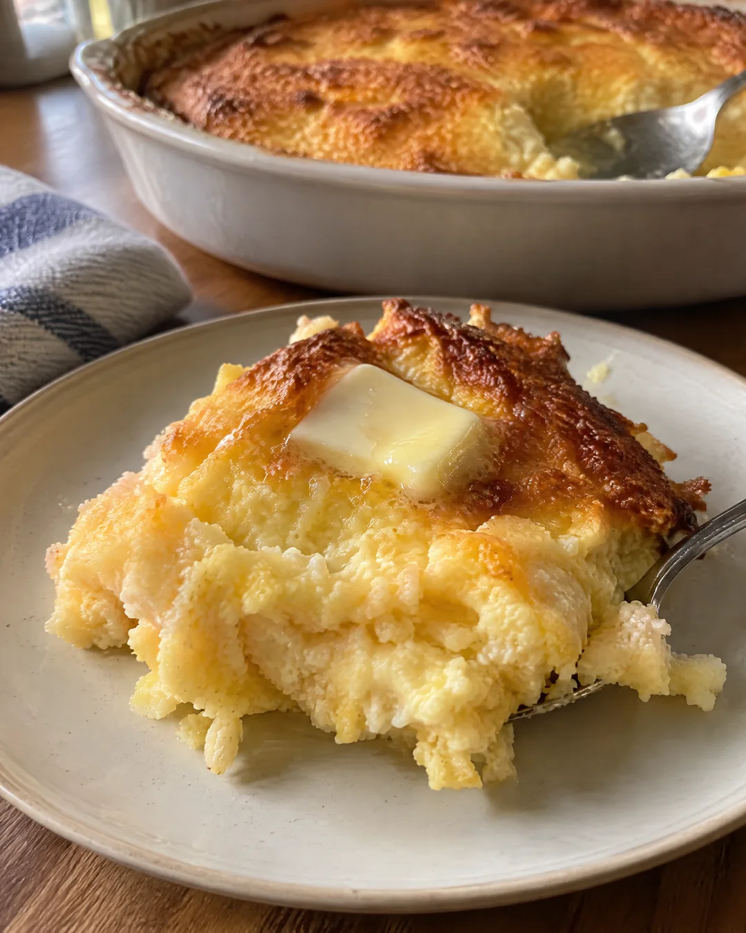 A spoonful of soft Southern spoon bread with melting butter on a plate