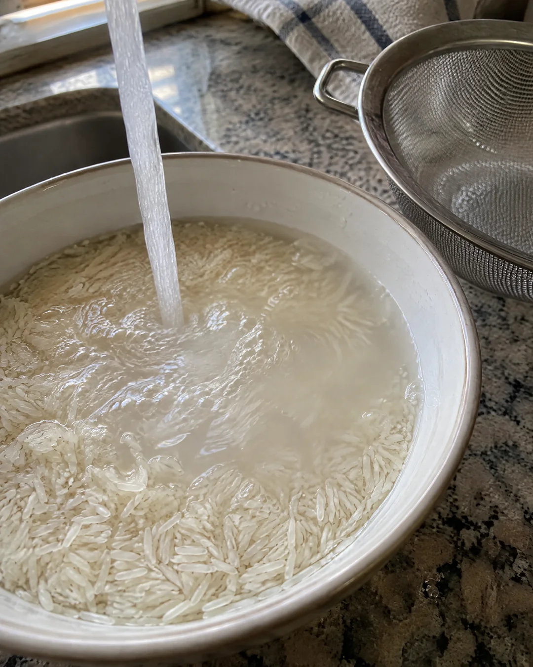 Rinsing long grain white rice in a bowl of cold water until it runs clear