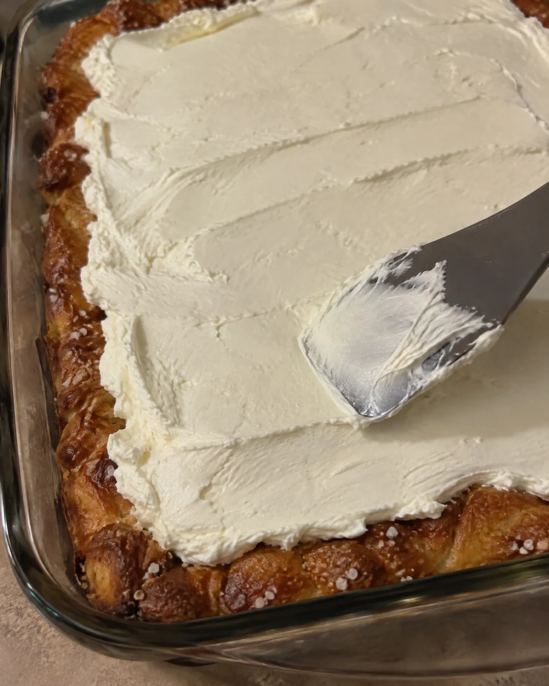 Spreading the cream cheese layer to the edges of the pan over the baked pretzel crust