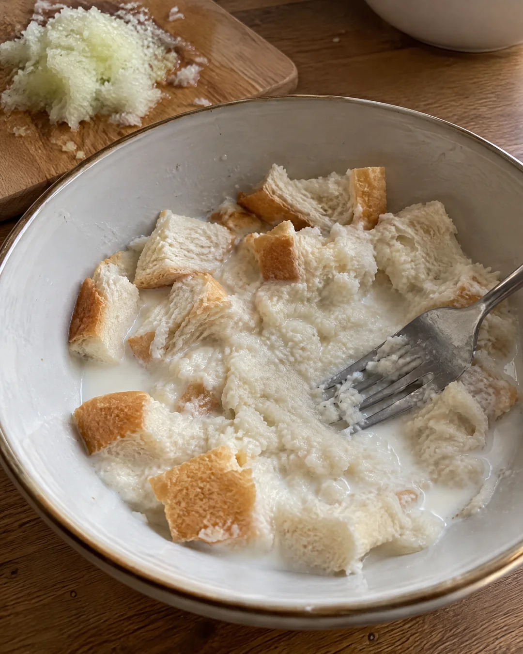 Torn bread soaking in milk in a bowl, the start of tender meatballs