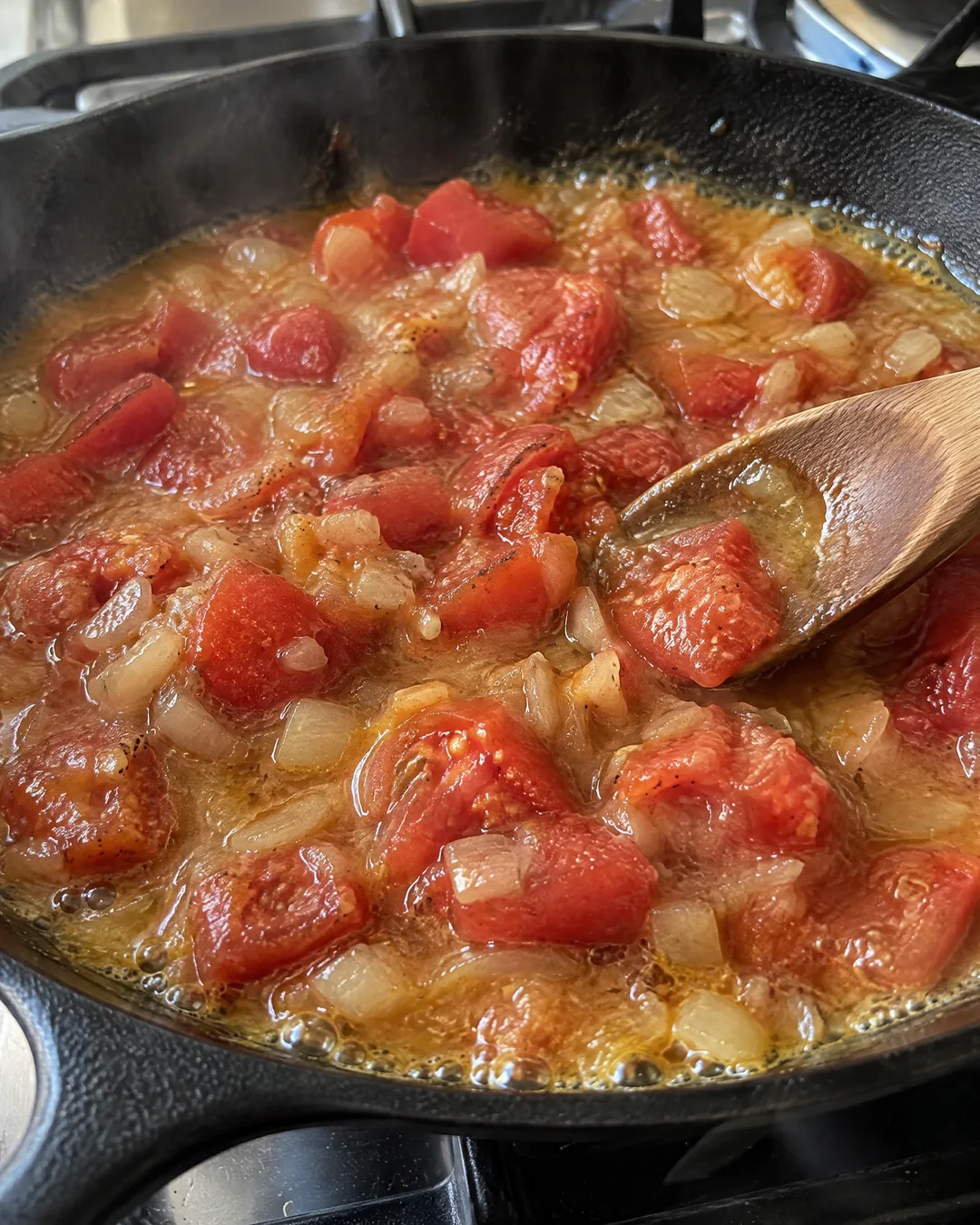 Chopped ripe tomatoes simmering in a skillet with softened onion and browned flour