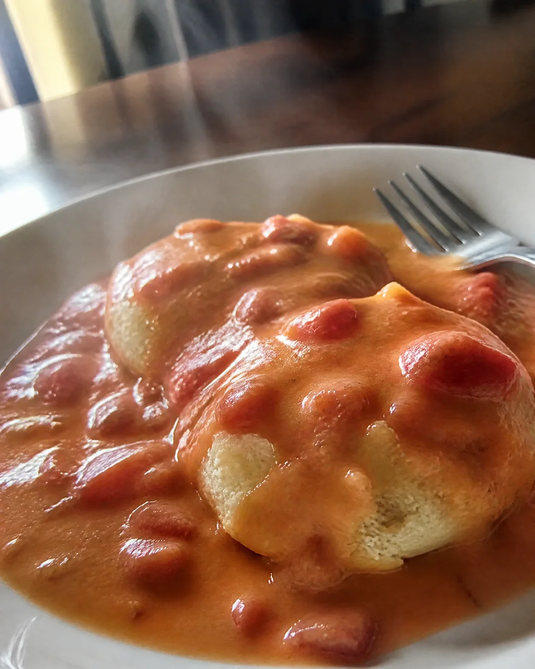 Tomato gravy poured over split hot buttermilk biscuits on a plate