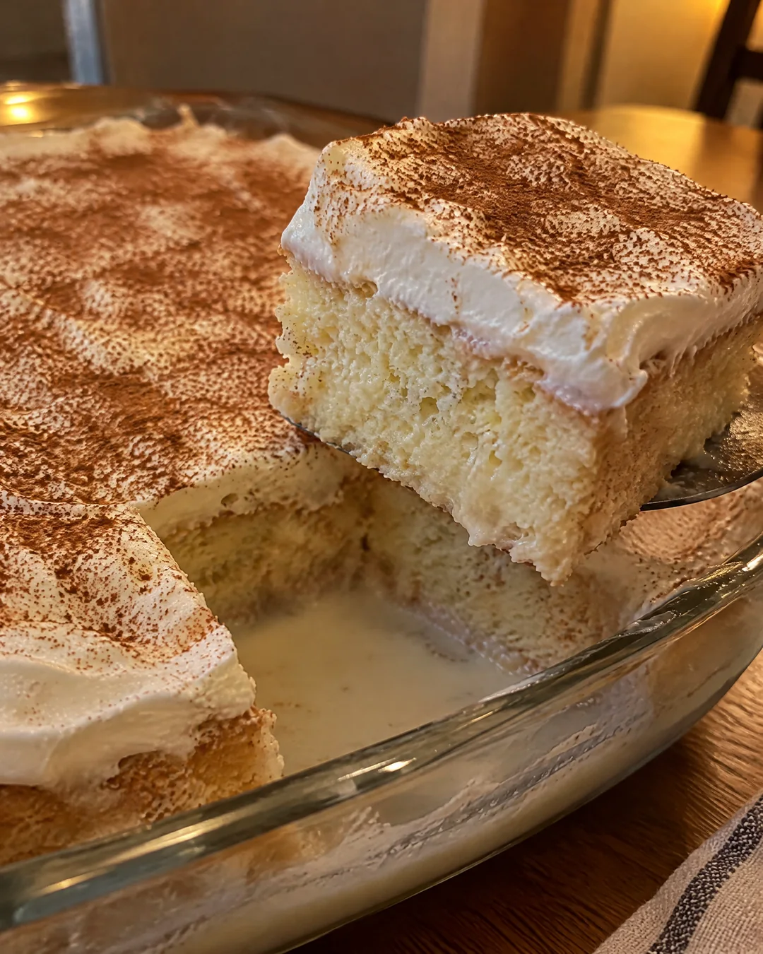 Tres leches cake with whipped cream and cinnamon, one square cut out
