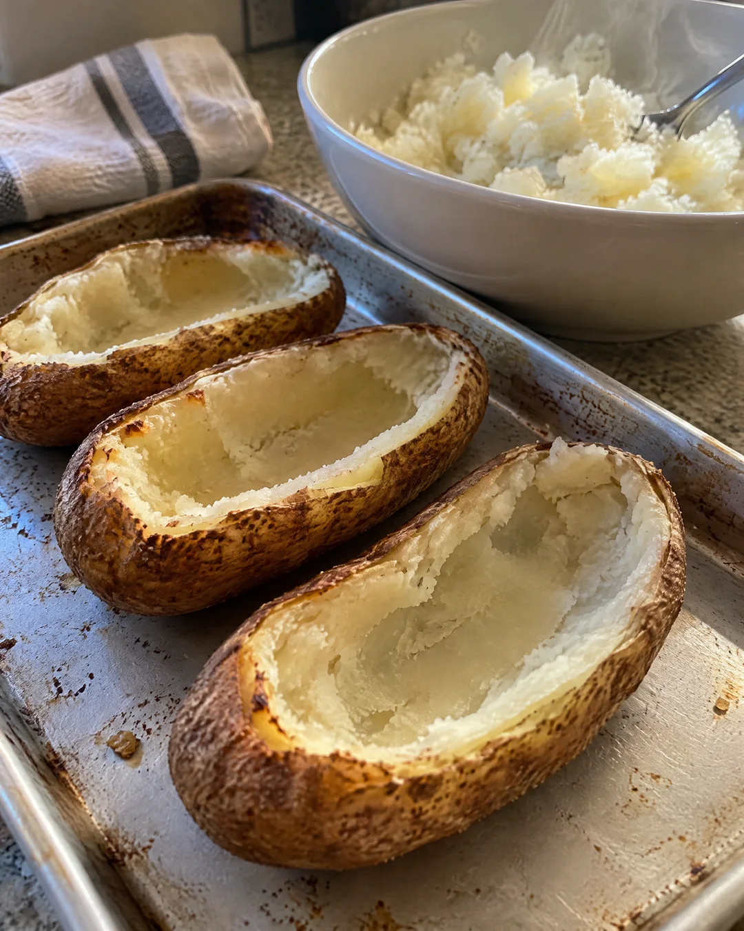 Baked potato halves scooped out with a thin wall of potato left in the skins